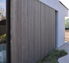 an exterior view of a house with wood slats on the wall and grass in front