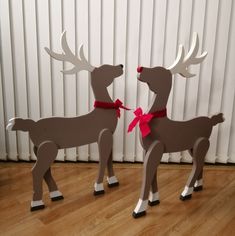 two wooden reindeer statues with red bows on their antlers