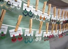 several pairs of earrings are hanging on clothes pegs with name tags attached to them