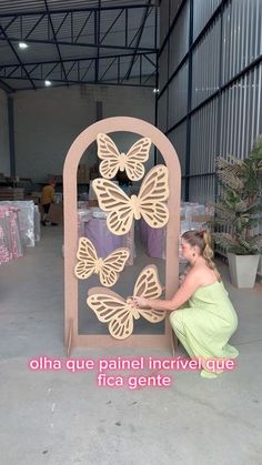 a woman kneeling down in front of a wooden sculpture with butterflies on it's side