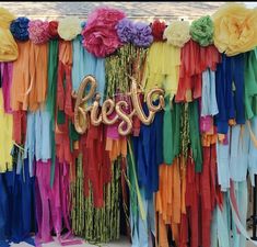 colorful streamers and balloons with the word fiesta spelled out in gold letters are hanging on a wall