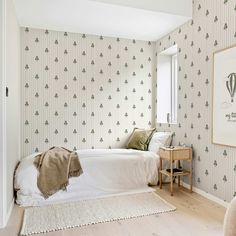 a bedroom with wallpaper and a bed in the corner, next to a window