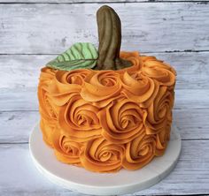 a cake decorated with orange icing and flowers on a white plate against a wooden background