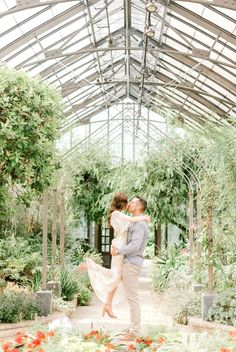 an engaged couple kissing in the greenhouse at their wedding