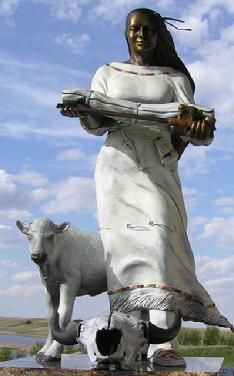 a statue of a woman with a goat in front of a body of water and blue sky