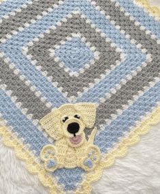 a crocheted afghan with a yellow dog on it's side and a blue border