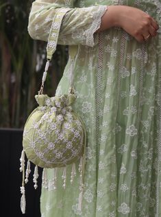 A delicately feminine green potli bag, that will be an ideal companion for all your ethnic ensembles. Its distinctive design features a wide handle, adorned with stunning pearl embroidery in florals. The entire bag is adored with elegant pearl work and embroidery, all in white, creating a subtle contrast. The elegance of the bag is accentuated by the pearl fringes that create a stunning movement.  Measurement: 23cm x 22cmHandle Drop: 24cm Designer Potli Bags, Partywear Suits, Pearl Work, Western Shop, Pearl Embroidery, Set Saree, Women's Bags By Style