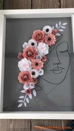 paper flowers in a white frame on a wooden table