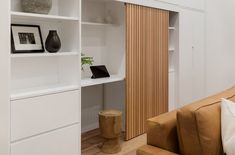 a living room filled with furniture and white shelves next to a wall mounted book shelf