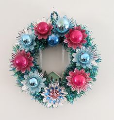 a christmas wreath hanging on the wall with ornaments around it's edges and decorations in different colors