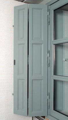 an open window in a room with white walls and blue shutters on the doors