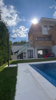 a house with a swimming pool in front of it and the sun shining through the windows