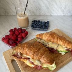 two croissants on a cutting board with strawberries and milk in the background