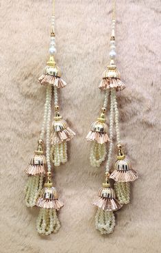 two pairs of gold and white beaded earrings with tassels hanging from them