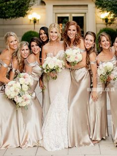 a group of women standing next to each other in front of a building with bouquets