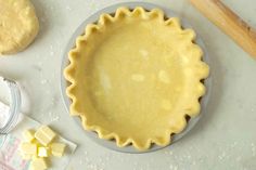 an uncooked pie crust sits on a table next to butter and other ingredients