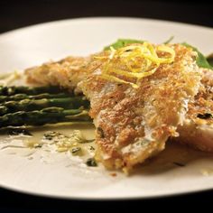 a white plate topped with fish and asparagus