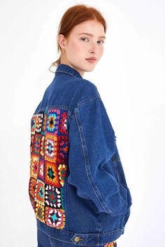 a woman wearing a denim jacket with colorful patches on the front and back, standing in front of a white background