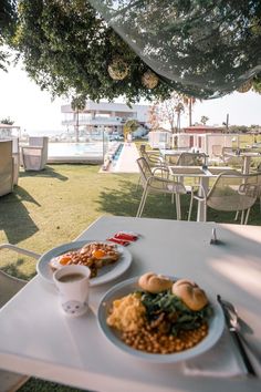 two plates of food are sitting on a white table in front of an outdoor dining area