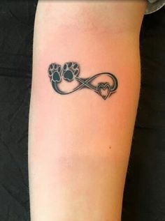 a dog paw and heart tattoo on the left arm, with an infinite love knot