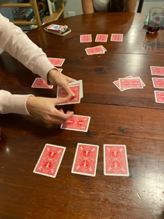 two people playing cards on a table with one person reaching for the other hand to grab it