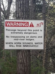 a warning sign posted on a tree in the woods