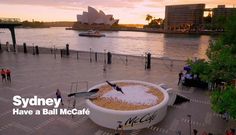 there is a giant coffee cup in the shape of a boat on the water and people are standing around it