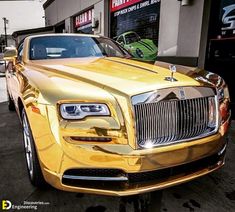 a gold rolls royce parked in front of a building