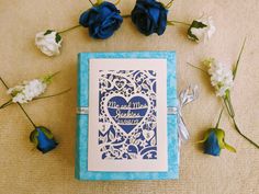 a blue and white card with a heart cut out in the middle surrounded by flowers