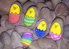 painted rocks with eggs and chicks on them sitting in the middle of some rocks that look like they're hatched into an egg