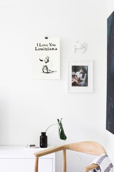 a white room with pictures on the wall and a wooden chair in front of it