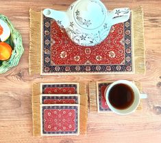 placemats, coasters, and coffee cups on a wooden table with oranges