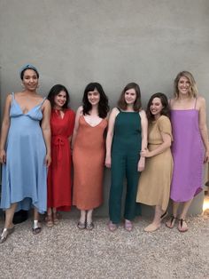 the women are posing for a photo together in their evening gowns and dresses, all wearing different colors