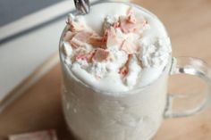 a cup filled with whipped cream on top of a wooden table