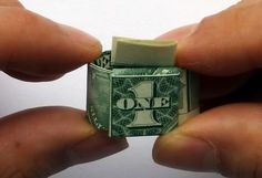 someone is holding a one dollar bill origami piece in their hands, with the money sticking out of it