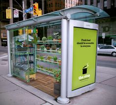 a bus stop on the side of the road with plants growing inside and in it's display case