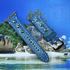 two blue watch bands sitting on top of each other in front of rocks and water