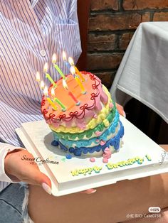 a person holding a birthday cake with lit candles