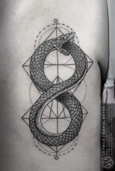 a woman's thigh with a snake and compass tattoo on the side of her stomach