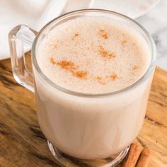 a glass mug filled with milk and cinnamon on top of a wooden cutting board