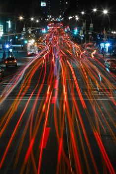 the city street is lit up with bright lights and blurry cars driving down it