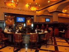 people sitting at tables in a restaurant with televisions on the wall and checkered floor