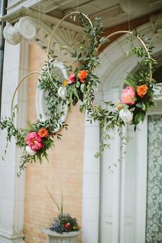 two hoop hanging from the ceiling with flowers and greenery on it's sides