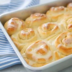 a pan filled with cinnamon rolls on top of a blue and white towel