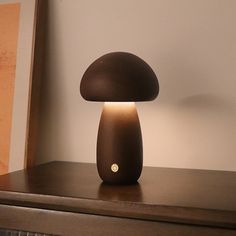 a mushroom shaped lamp sitting on top of a wooden table next to a framed photograph