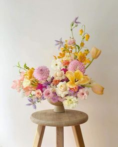 a wooden stool holding a vase filled with flowers