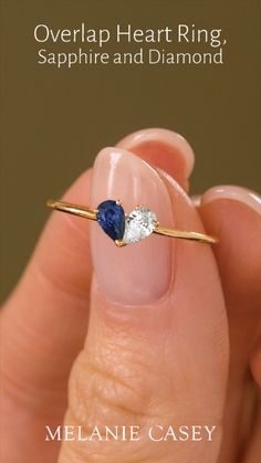 a hand holding a blue and white ring with two diamonds on it's finger