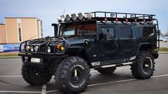 a black hummer truck parked in a parking lot with its lights on and four wheel drive