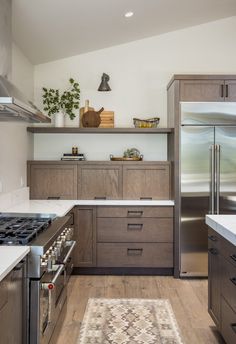 a modern kitchen with stainless steel appliances and wood cabinetry, along with a rug on the floor