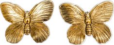 two gold butterfly shaped brooches sitting next to each other